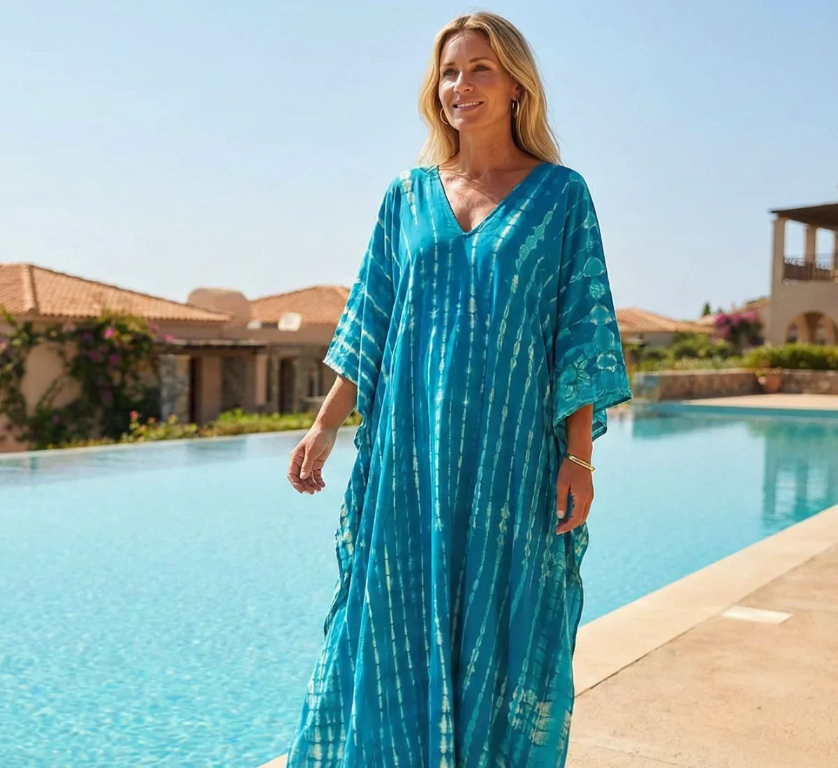 the statement kaftan woman wearing aqua blue kaftan standing by pool
