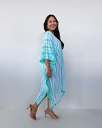 Woman wearing a light blue and white striped dress against a white background