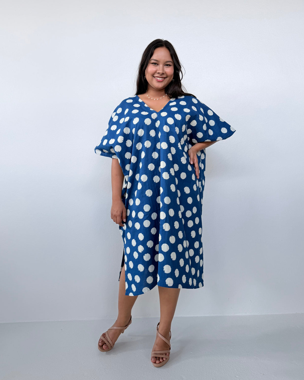 Woman wearing a blue dress with white polka dots against a white background