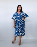 Woman wearing a blue dress with white polka dots against a white background