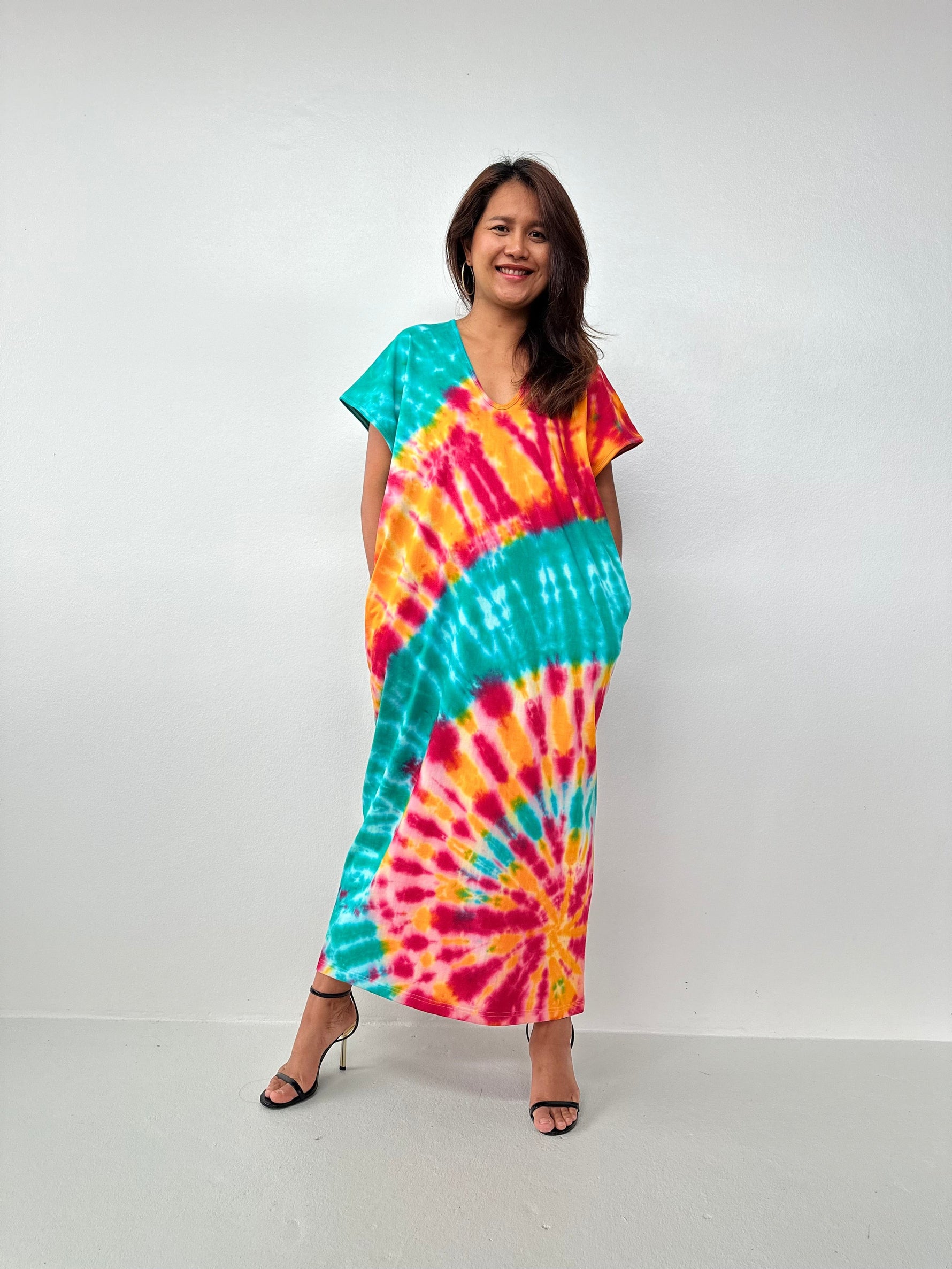 Woman wearing a colorful tie-dye dress against a white background