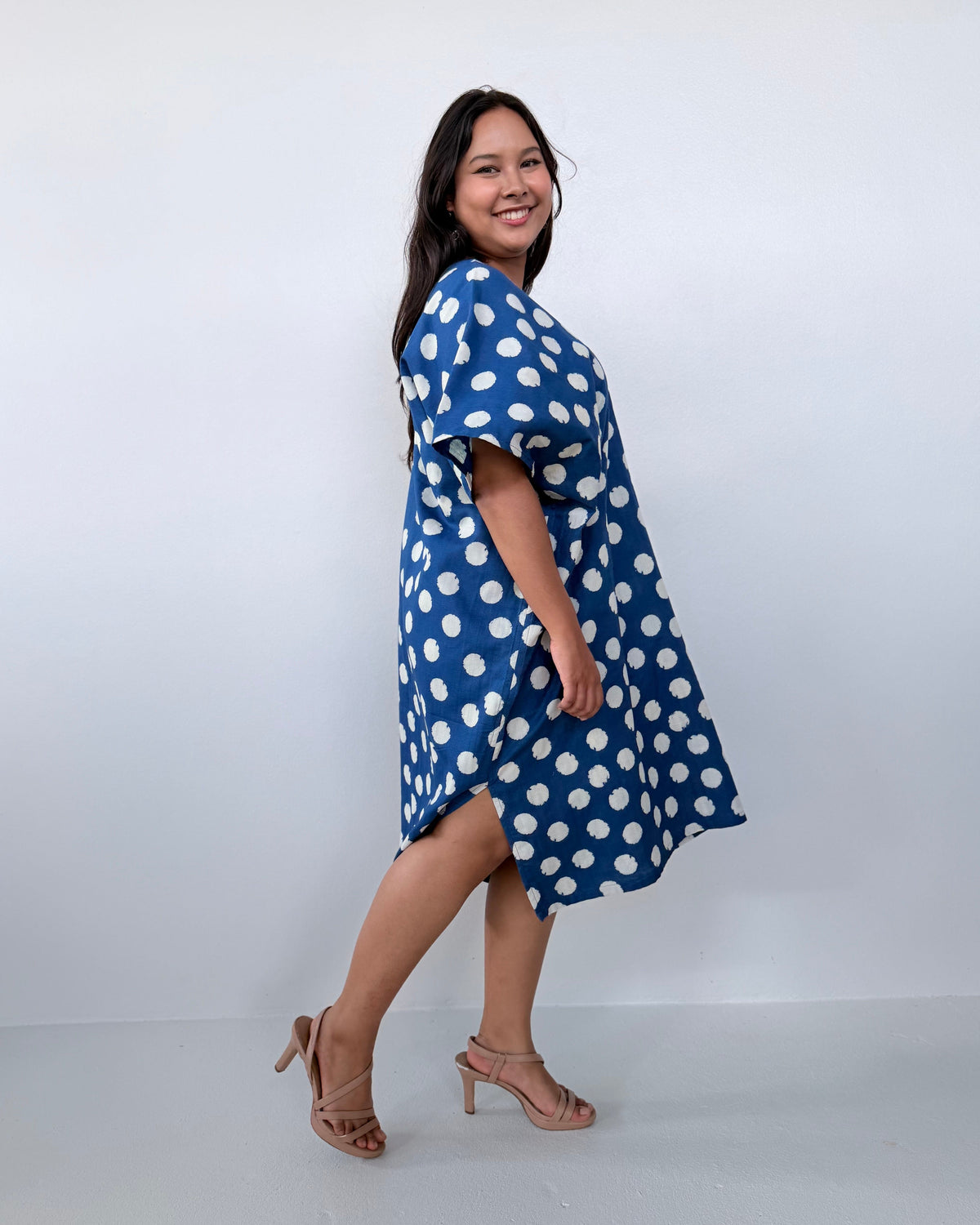 Woman wearing a blue dress with white polka dots against a white background