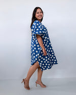 Woman wearing a blue dress with white polka dots against a white background