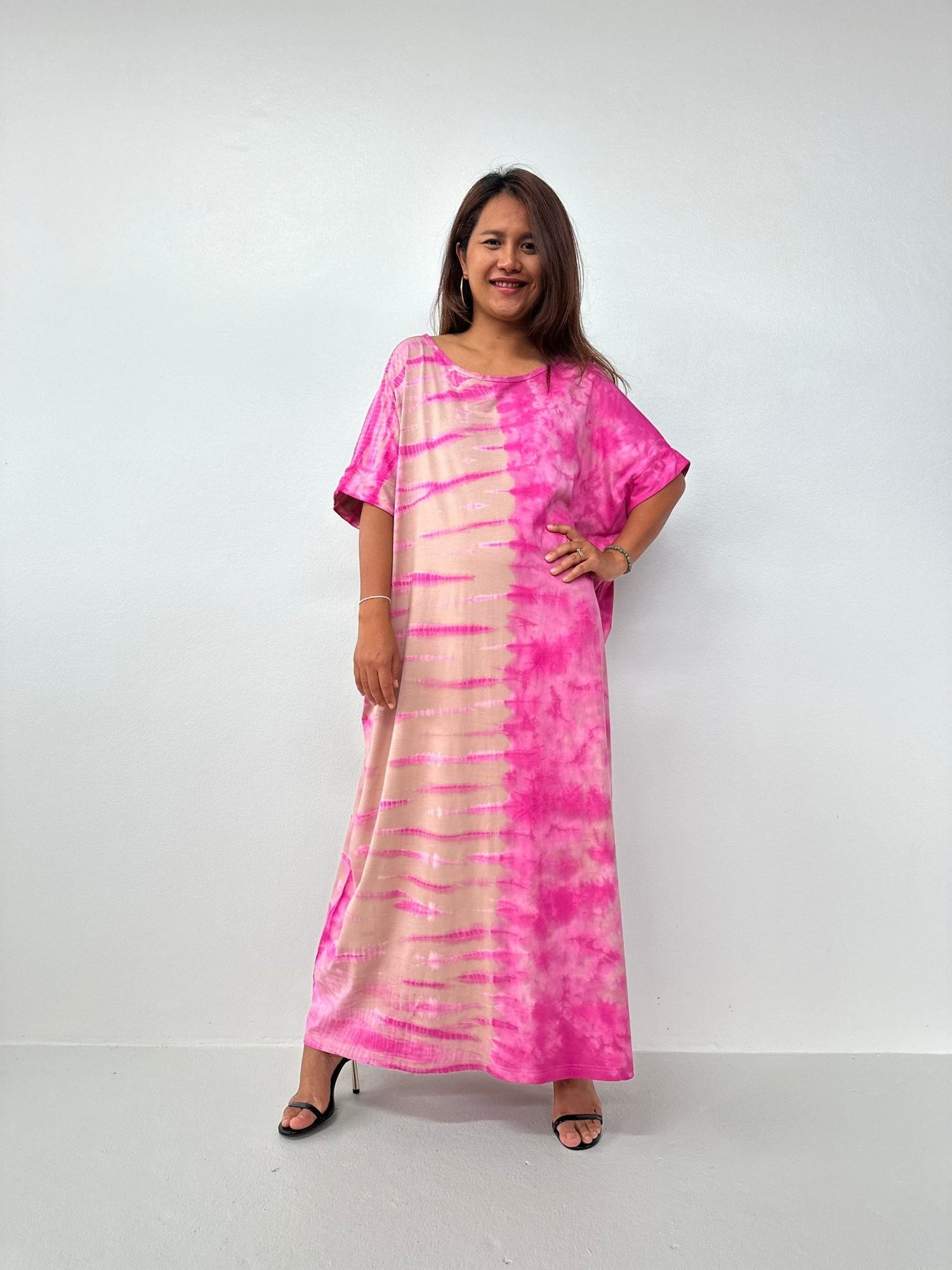 Woman wearing a pink and beige tie-dye dress on a white background