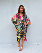 Woman wearing a colorful dress against a white wall