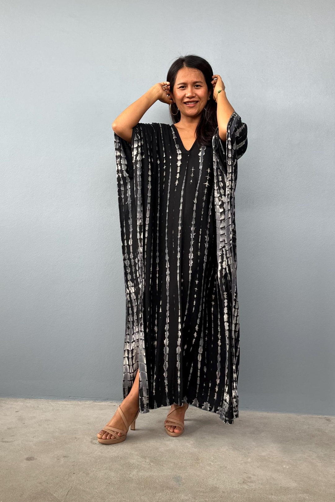 Woman wearing a black and white patterned dress against a gray background