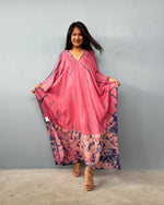 Woman wearing a pink dress with floral patterns on a gray background
