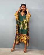 Woman wearing a green dress with a yellow and brown kimono-style cover-up against a gray background