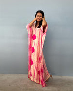 Woman wearing a pink and red patterned dress against a gray background