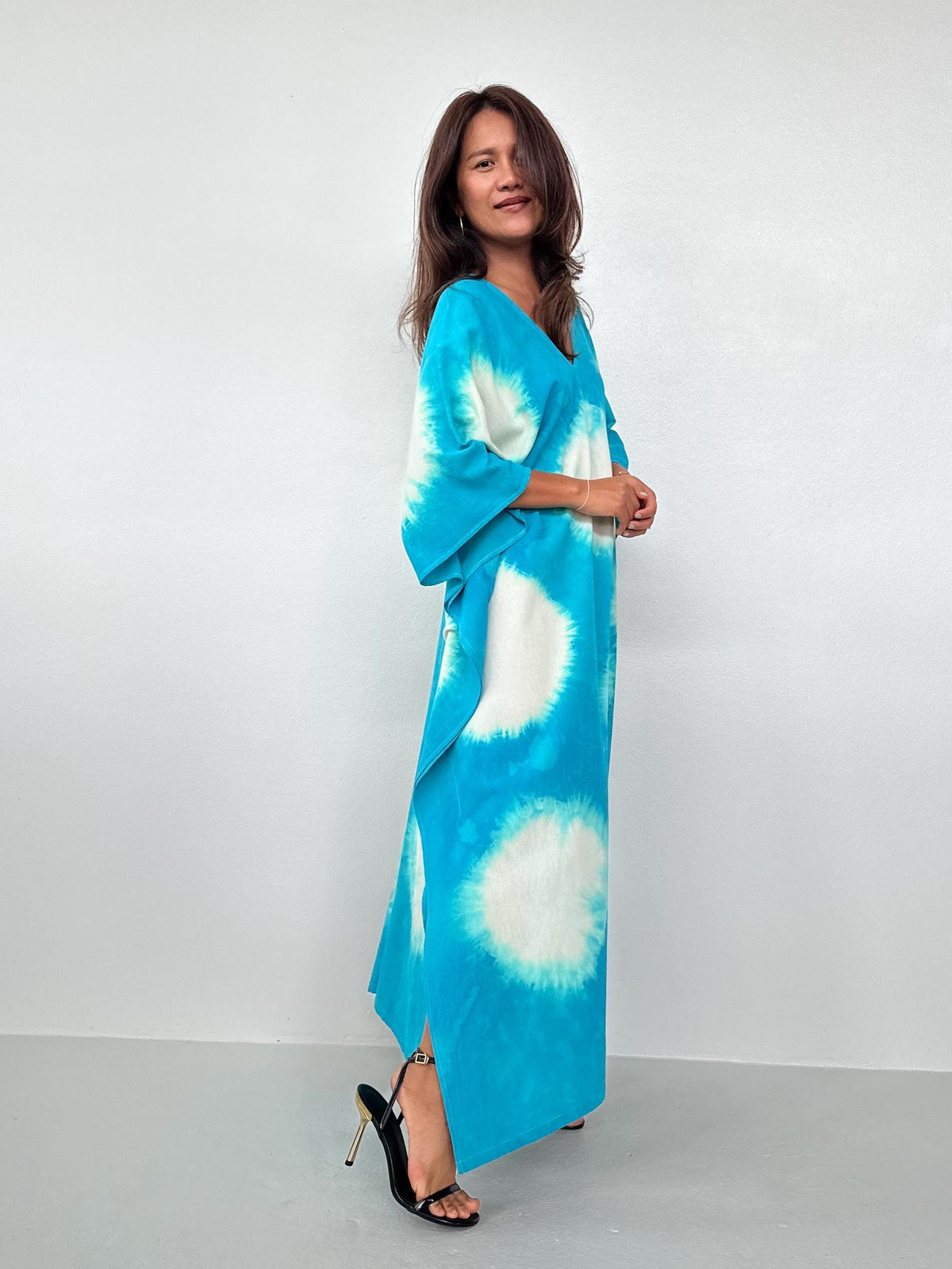 Woman wearing a blue tie-dye dress against a white background