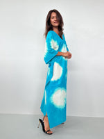 Woman wearing a blue tie-dye dress against a white background