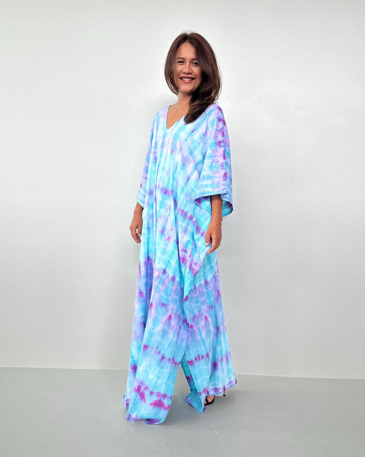 Woman wearing a tie-dye dress against a plain background