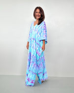 Woman wearing a tie-dye dress against a plain background