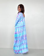 Woman wearing a blue and purple tie-dye dress against a white background