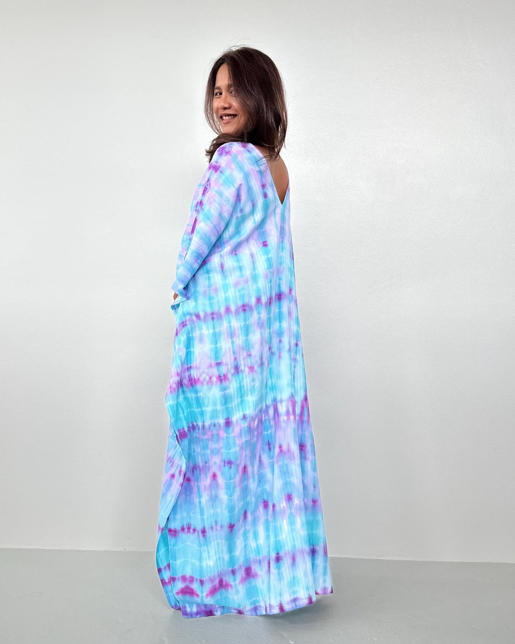 Woman wearing a blue and purple tie-dye dress against a white background