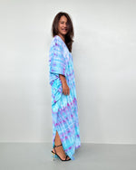 Woman wearing a tie-dye dress on a plain background