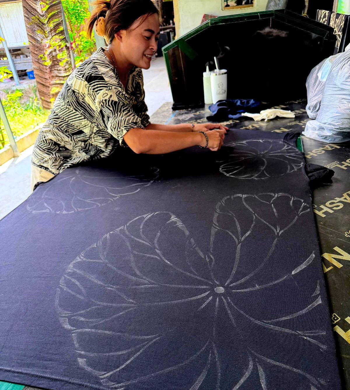 artist hand-painting lotus leaves onto kaftan