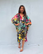 Woman wearing a colorful dress against a white wall