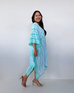 Woman wearing a light blue and white striped dress against a white background