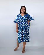 Woman wearing a blue dress with white polka dots against a white background