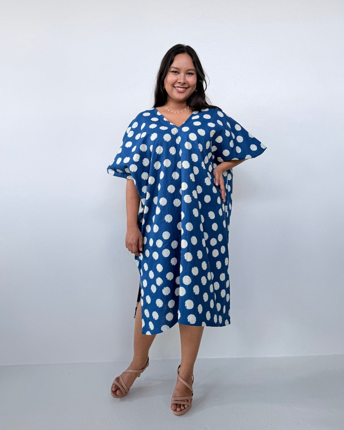 Woman wearing a blue dress with white polka dots against a white background