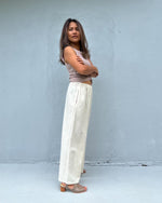 Woman wearing a sleeveless top and wide-leg pants against a plain background