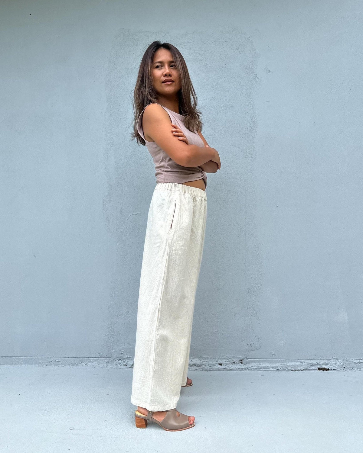 Woman wearing a sleeveless top and wide-leg pants against a plain background